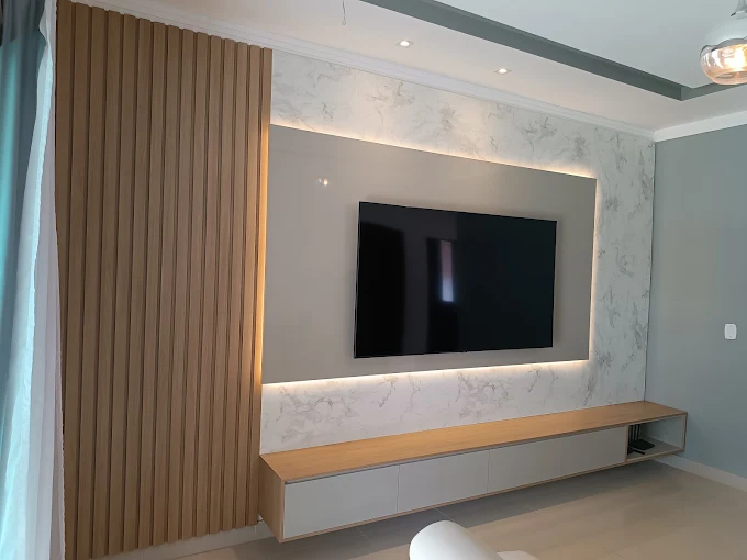 Painel ripado de madeira com rack suspenso e iluminação embutida na sala